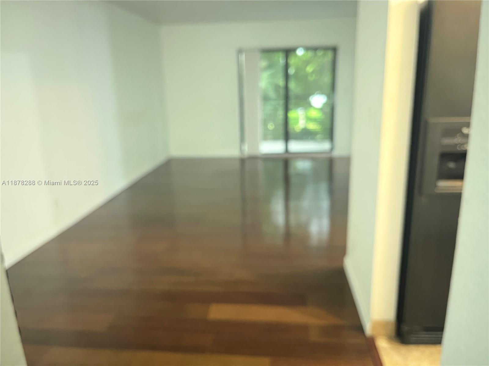 An empty room features dark wood flooring, white walls, and a sliding glass door — 3720 N Pine Island Rd # 331, Sunrise FL 33351, SUNRISE, FL
