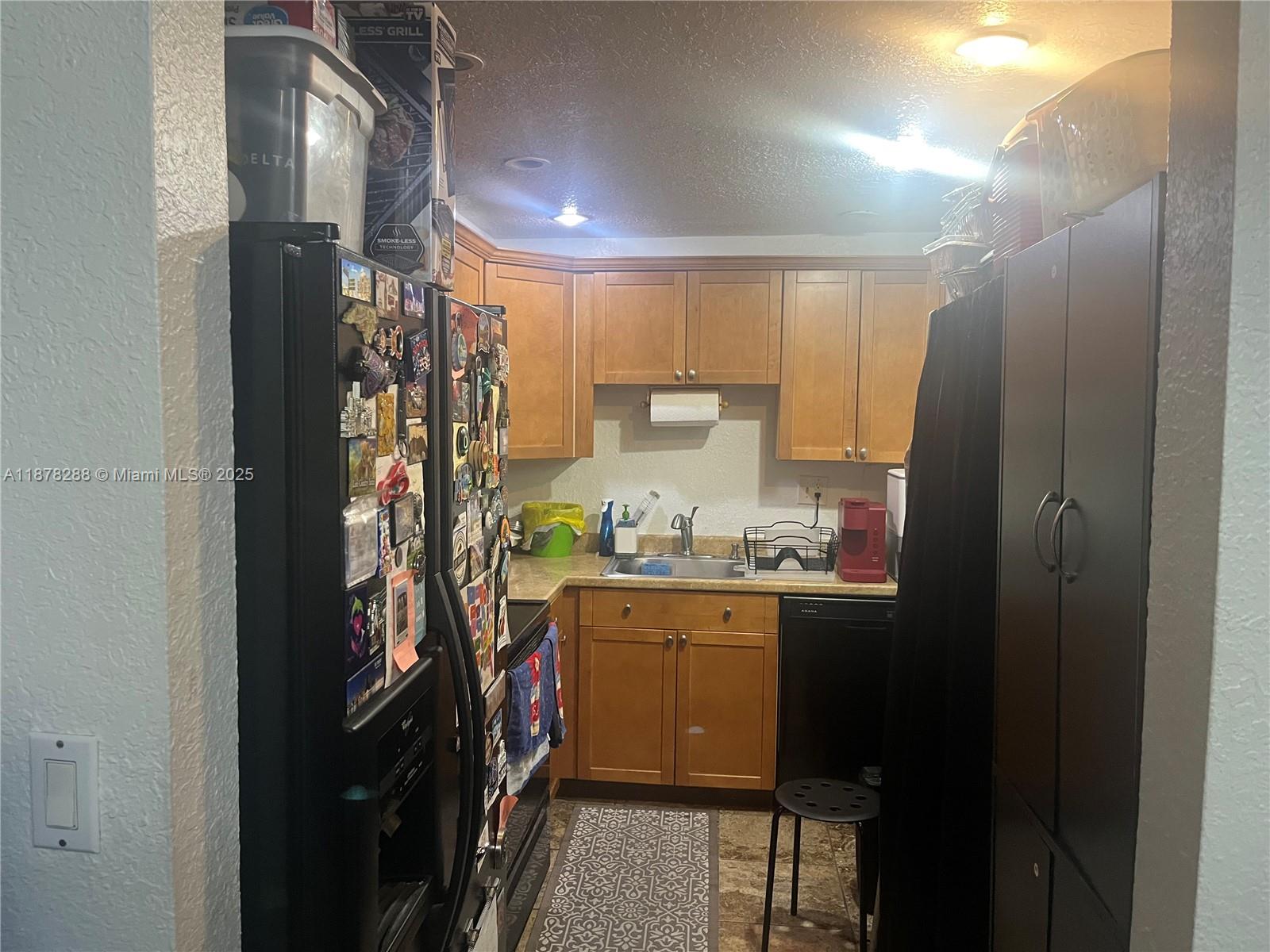 A small kitchen features wood cabinets, a black refrigerator, a sink, and a dishwasher — 3720 N Pine Island Rd # 331, Sunrise FL 33351, SUNRISE, FL