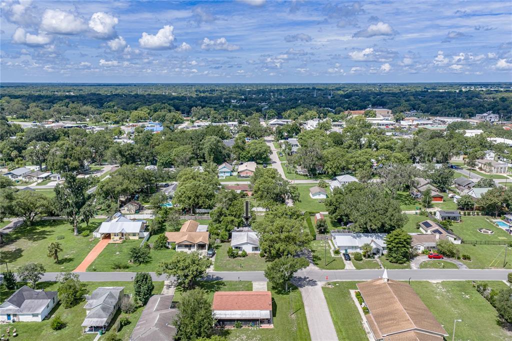 An aerial view shows a single-story house with a white roof in a residential neighborhood — 5207 10TH STREET, ZEPHYRHILLS, FL