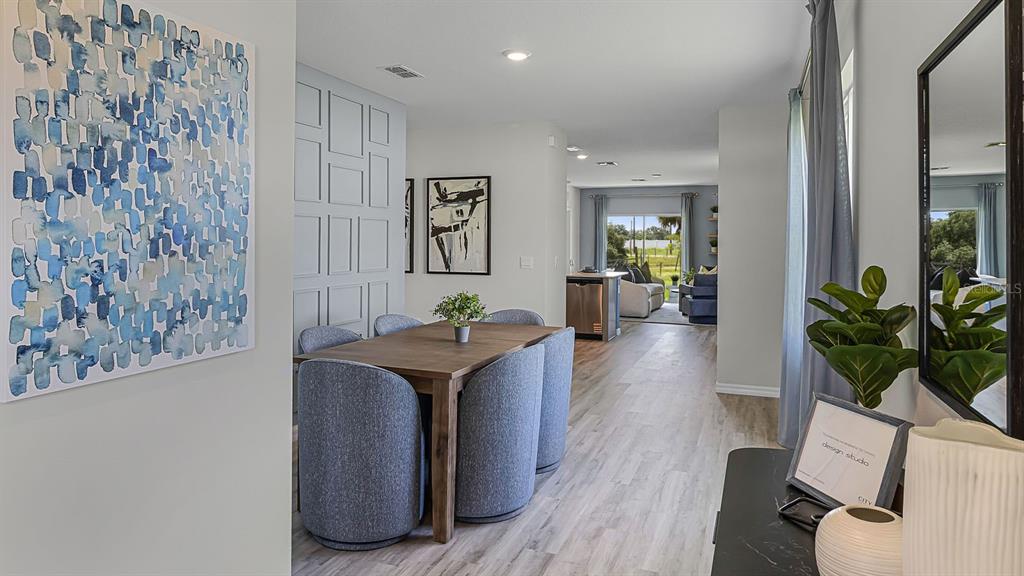 A dining area with a wooden table and blue chairs leads into a living room — 4811 KHLOE COURT, WINTER HAVEN, FL