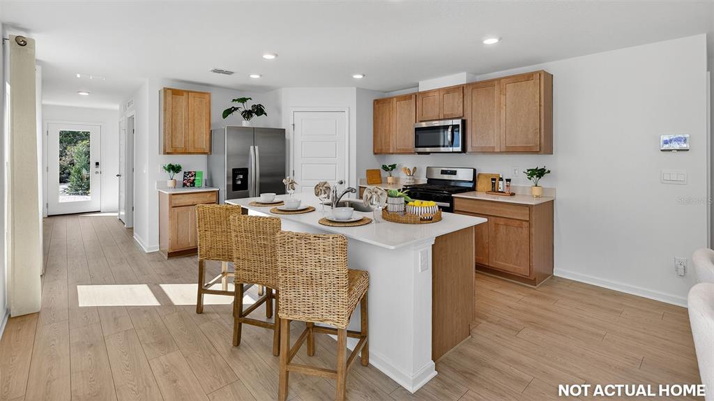 This rendering shows a kitchen with light wood cabinets, a white island, and stainless appliances — 16 FLAGSTICK LANE, BUNNELL, FL