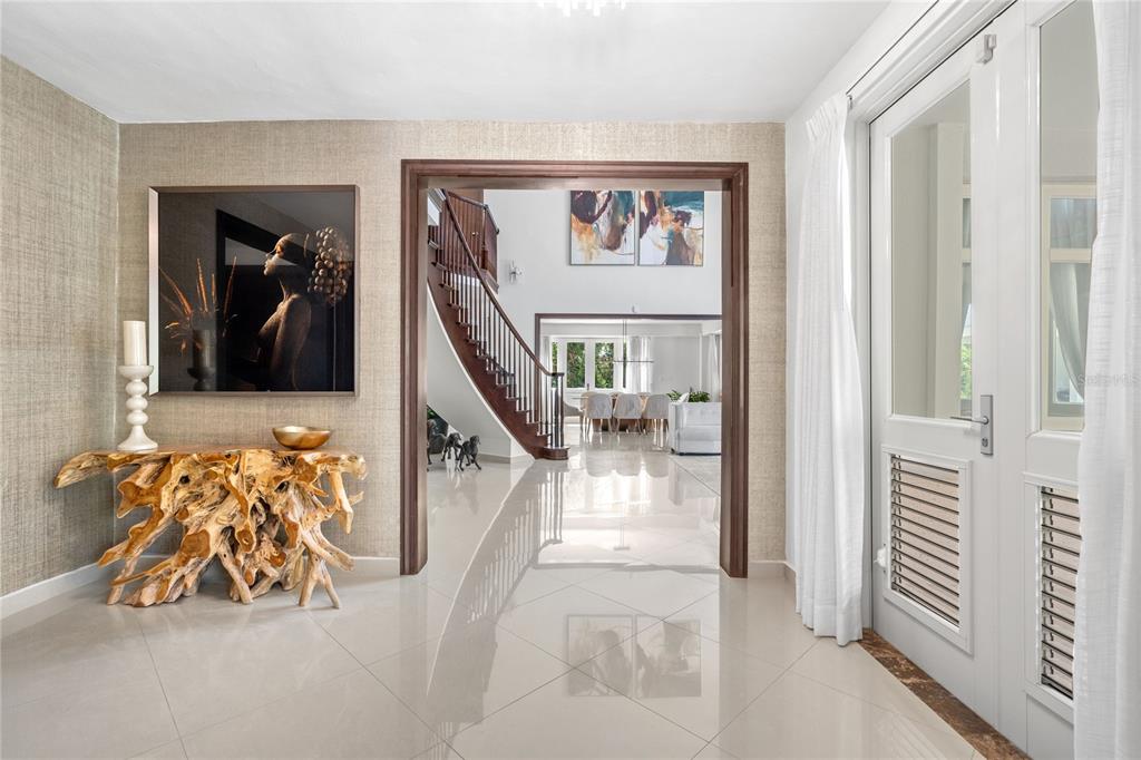 A foyer with a natural wood console table, textured wallpaper, and a view of stairs — 446 DORADO BEACH EAST, DORADO, PR