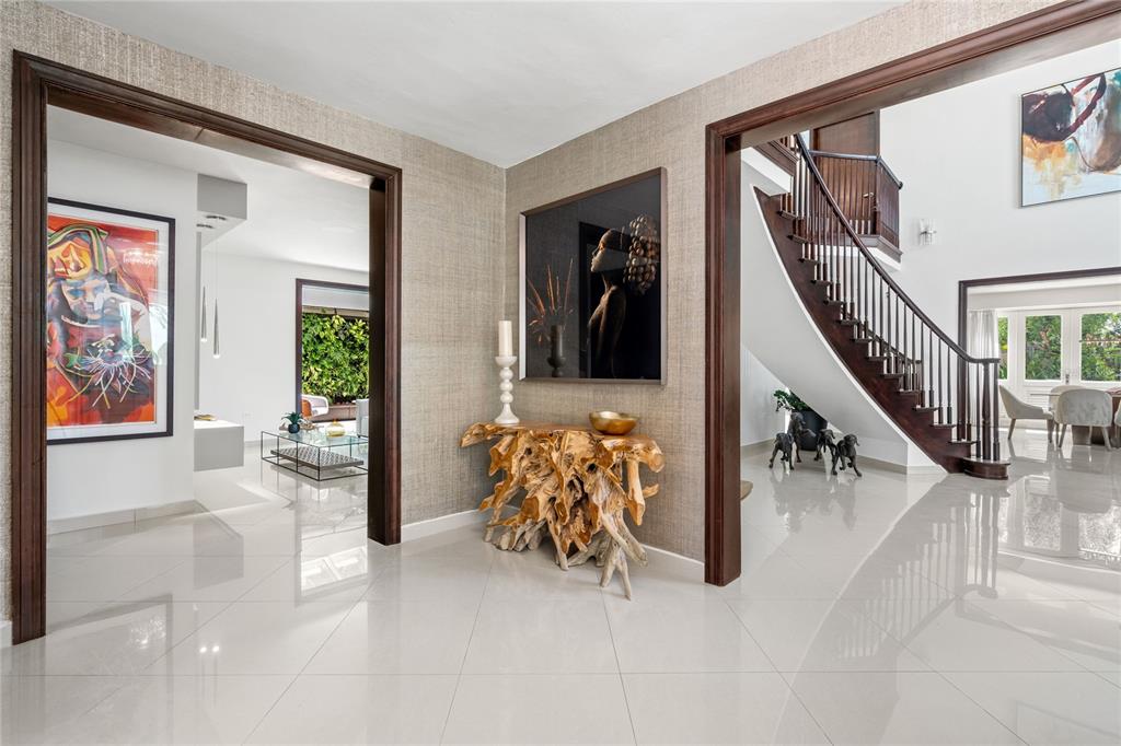 A foyer with white tile floors, a wooden console table, and a curved staircase — 446 DORADO BEACH EAST, DORADO, PR