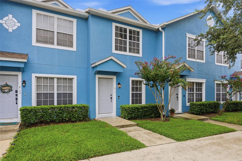 A row of blue two-story townhomes features white trim, front doors, and small landscaped lawns — 417 WILTON CIRCLE, SANFORD, FL