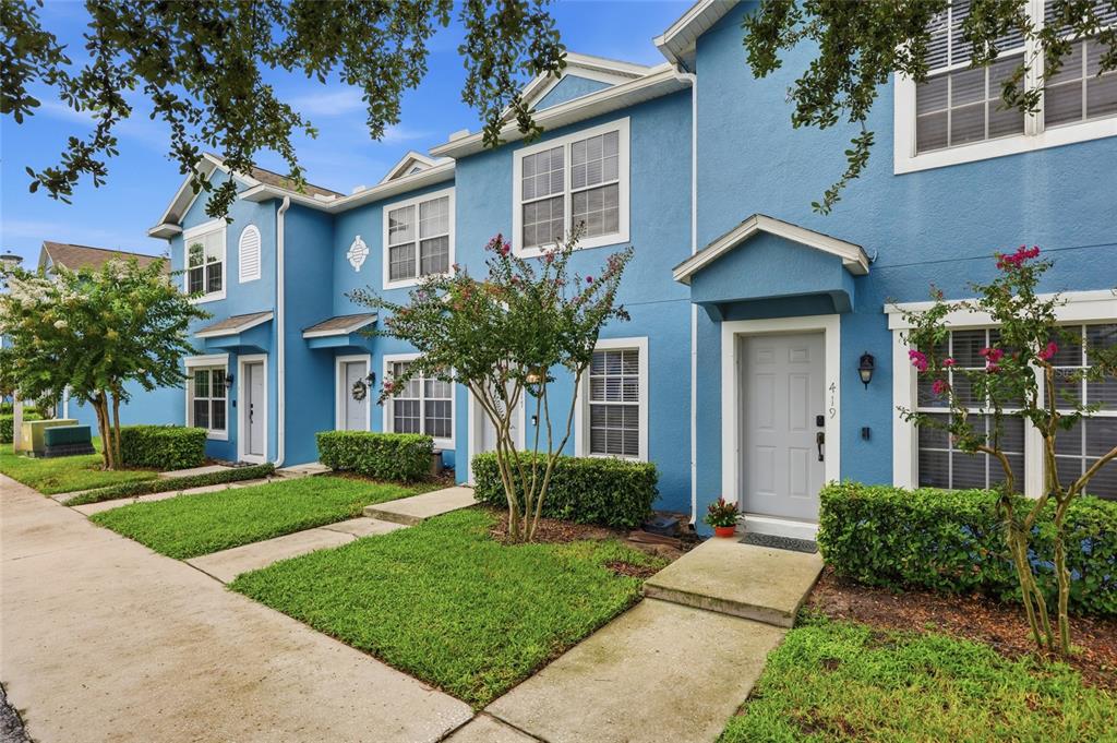 A row of blue two-story townhouses with gray front doors and small front lawns — 417 WILTON CIRCLE, SANFORD, FL