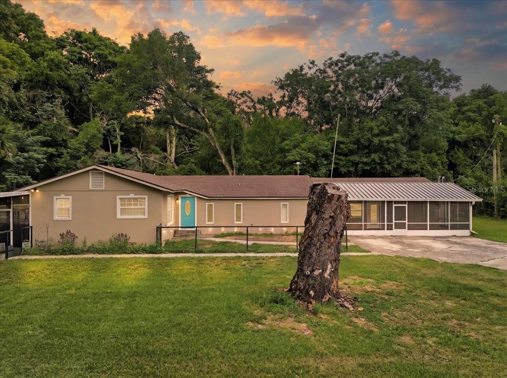 A single-story house with a tan exterior, a bright blue front door, and a screened porch — 8095 ROSE AVENUE, ORLANDO, FL