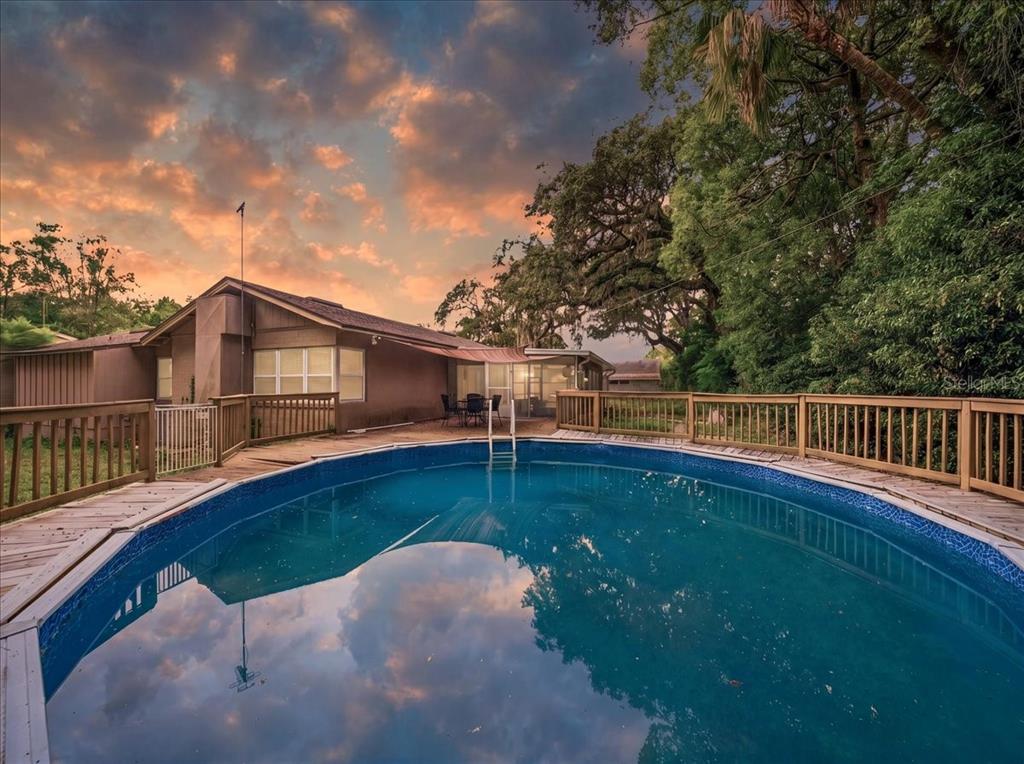 An above-ground swimming pool sits on a wooden deck behind a single-story house — 8095 ROSE AVENUE, ORLANDO, FL