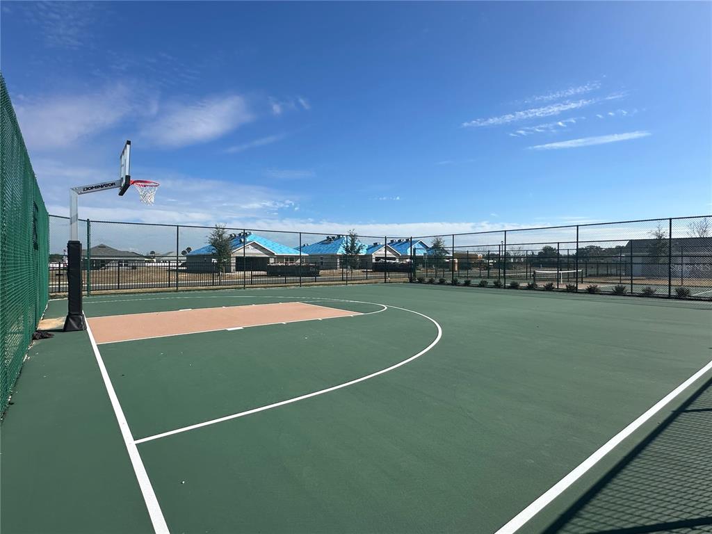 An outdoor basketball court with a green surface and a chain-link fence enclosure — 12539 NE 48TH TERRACE, OXFORD, FL