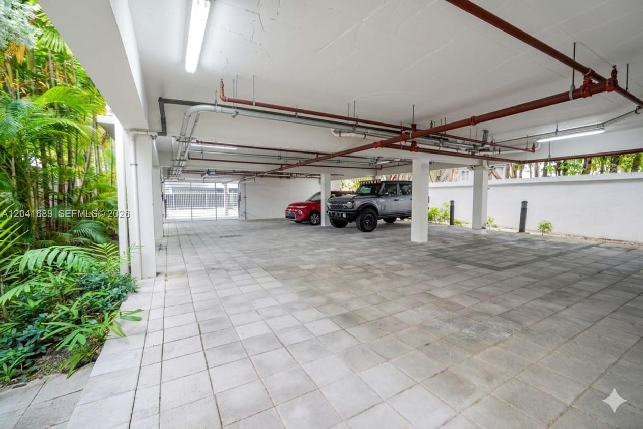 A covered parking area features concrete tile flooring, white support columns, and exposed overhead pipes — 619 Meridian Ave # 4, Miami Beach FL 33139, MIAMI BEACH, FL