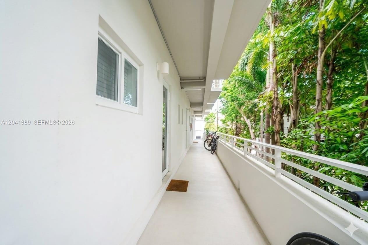 A long, white outdoor balcony features a metal railing and overlooks lush green trees — 619 Meridian Ave # 4, Miami Beach FL 33139, MIAMI BEACH, FL