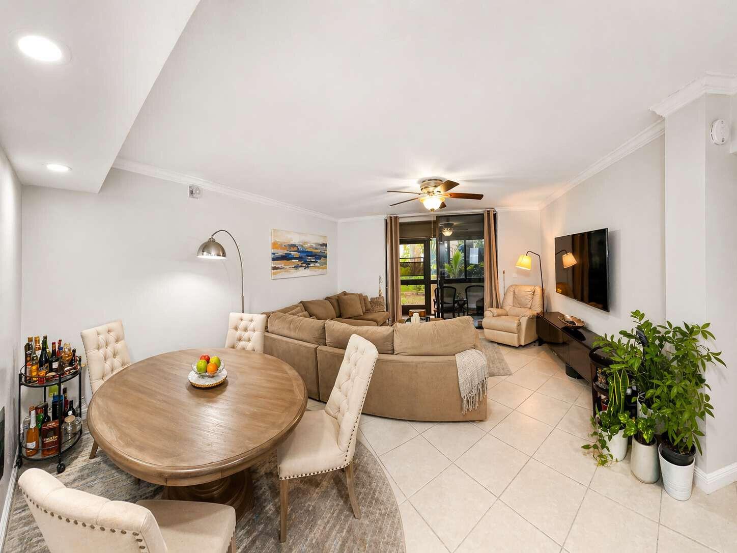 A living and dining room with a round wooden table, sectional sofa, and tile flooring — 5160 Las Verdes Circle # 103, Delray Beach FL 33484, DELRAY BEACH, FL