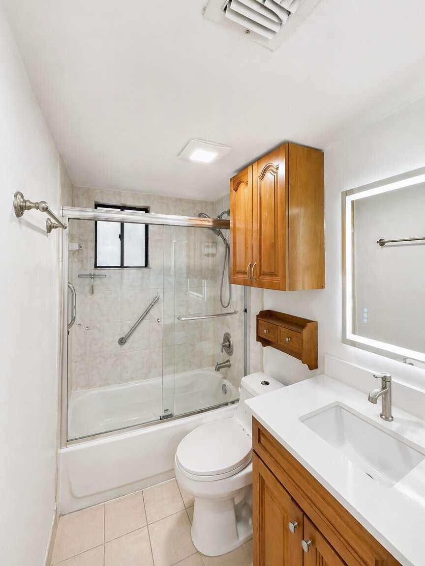 A bathroom features a tub-shower combo, a wood vanity, and a wall-mounted medicine cabinet — 5160 Las Verdes Circle # 103, Delray Beach FL 33484, DELRAY BEACH, FL