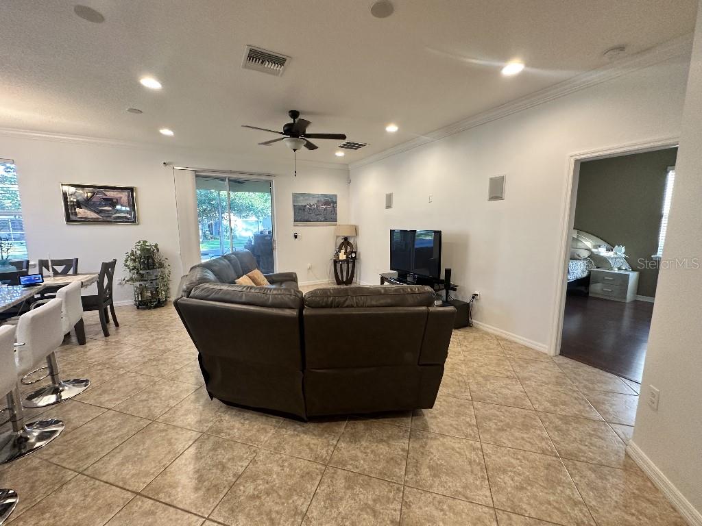 A living room features tile flooring, a leather sectional sofa, and a television on a stand — 11248 MOLLYMAWK COURT, NEW PORT RICHEY, FL