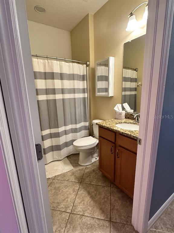 A bathroom features a shower with a striped curtain, a toilet, and a wood vanity — 11248 MOLLYMAWK COURT, NEW PORT RICHEY, FL