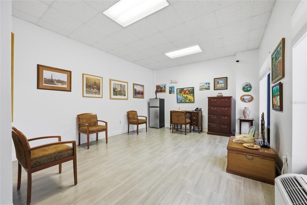 A room with light wood-look flooring, white walls, multiple framed paintings, and several wooden chairs — 30924 SUNEAGLE DRIVE UNIT Suite 201-203, MOUNT DORA, FL