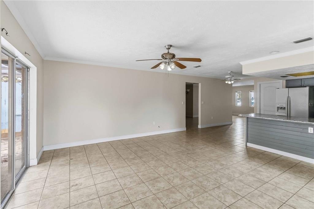 A tiled living area features a ceiling fan, sliding glass doors, and a kitchen island — 16329 CARIBBEAN COURT, HUDSON, FL