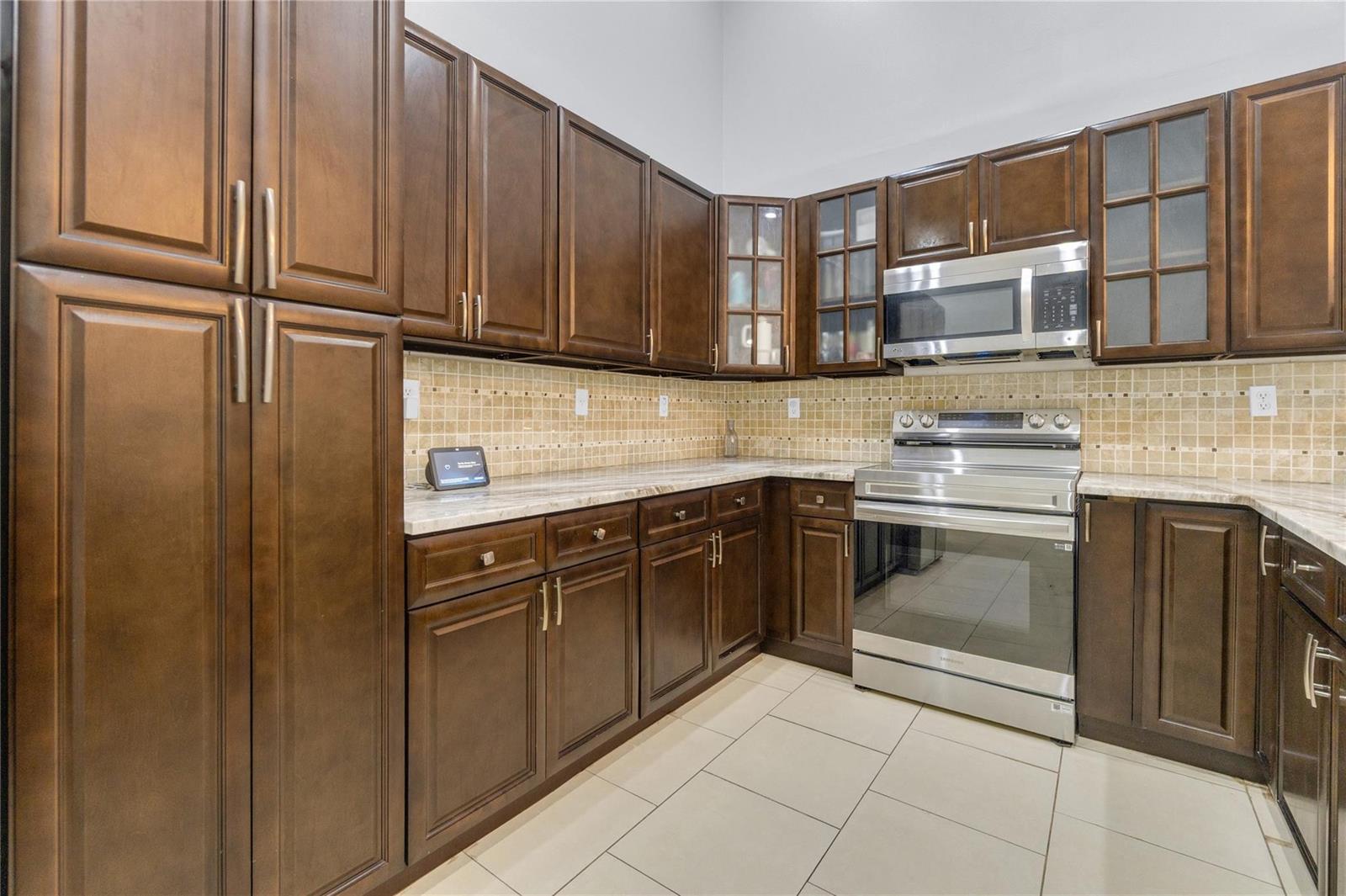 A kitchen features dark wood cabinets, stainless steel appliances, and a light-colored stone countertop — 3003 La Mirage # 3003, Lauderhill FL 33319, LAUDERHILL, FL