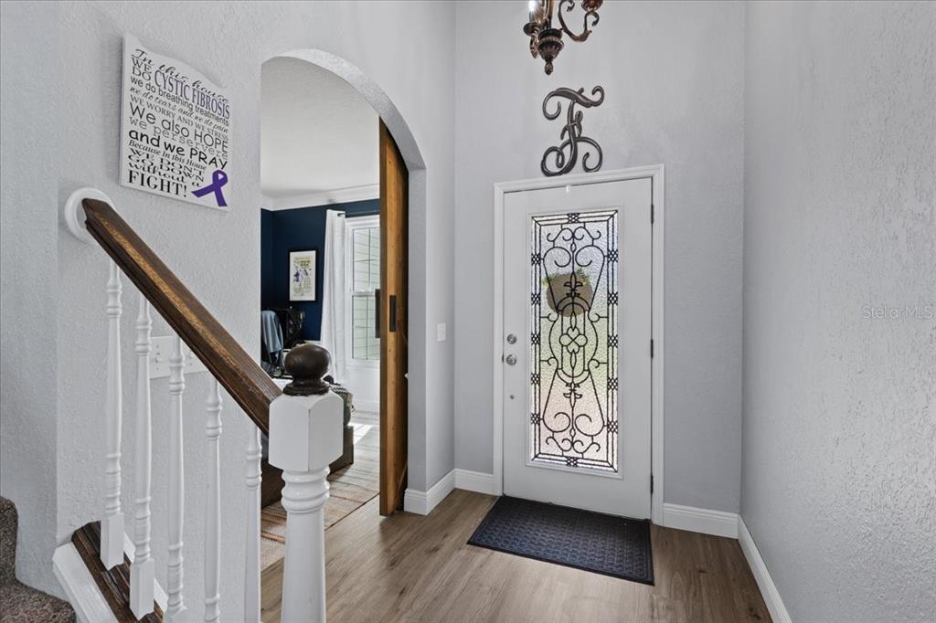 An entryway features a white front door with decorative glass, wood-look flooring, and a staircase — 2600 SE 48TH AVENUE, TRENTON, FL