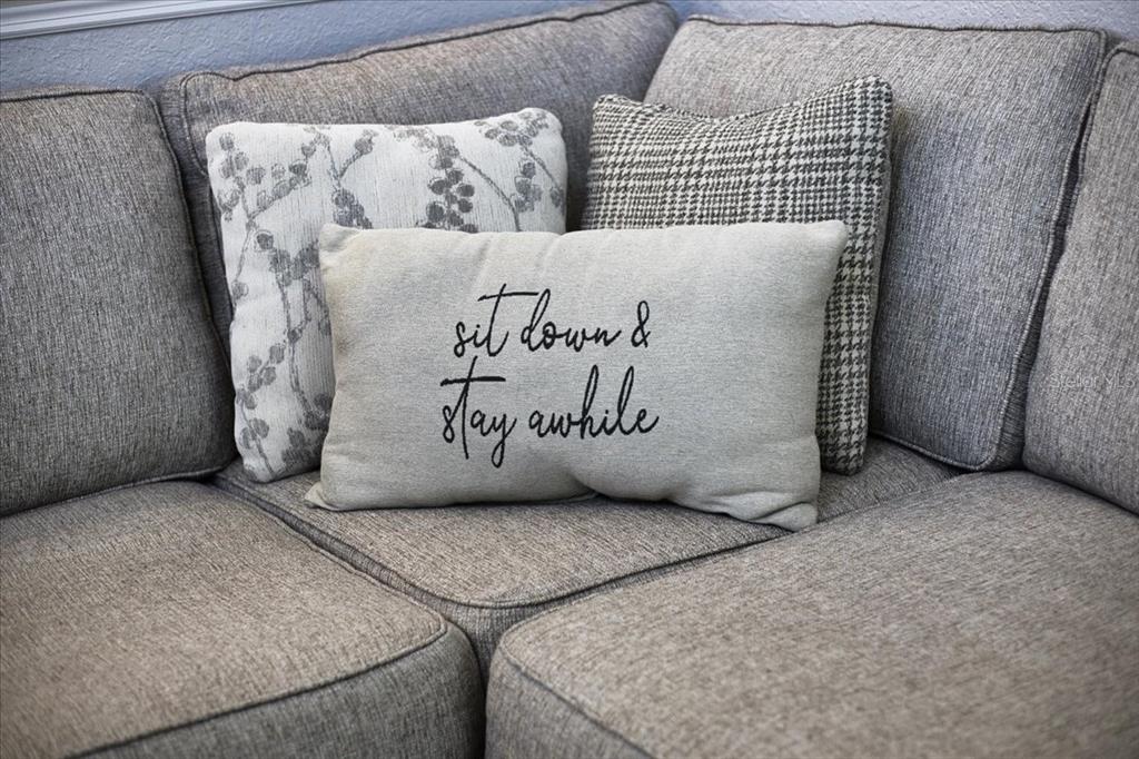 A gray sectional sofa features three decorative throw pillows, including one with text — 2600 SE 48TH AVENUE, TRENTON, FL