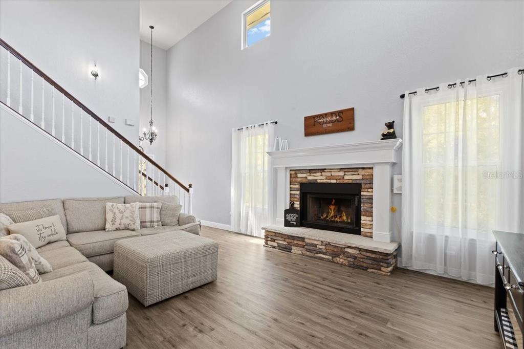 A living room features a stone fireplace, a staircase with white railings, and light flooring — 2600 SE 48TH AVENUE, TRENTON, FL