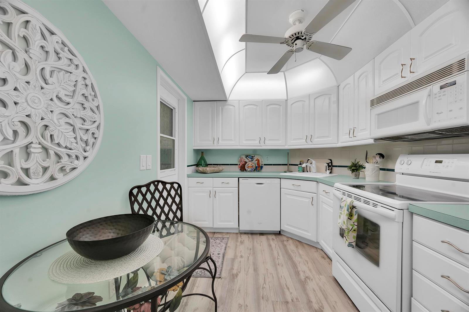 A kitchen with white cabinets, light green countertops, and a glass-topped dining table — 3492 NE Causeway Boulevard # 103, Jensen Beach FL 34957, JENSEN BEACH, FL