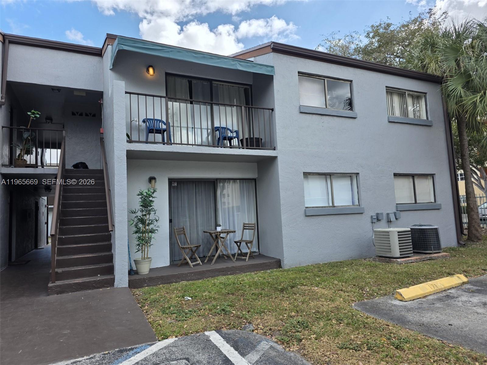 A two-story apartment building with a ground-floor patio, second-floor balcony, and exterior staircase — 7421 SW 152nd Ave # 101, Miami FL 33193, MIAMI, FL