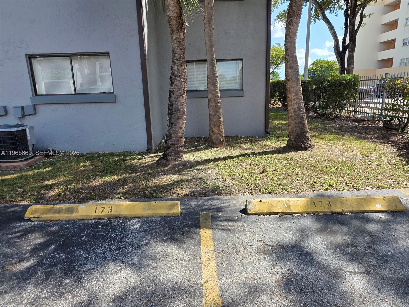 An exterior view shows a gray building wall with two windows, palm trees, and parking spaces — 7421 SW 152nd Ave # 101, Miami FL 33193, MIAMI, FL