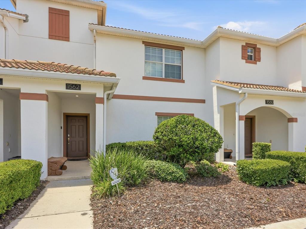 The exterior of two adjacent townhouses features white stucco walls, brown trim, and tiled roofs — 1562 MOON VALLEY DRIVE, DAVENPORT, FL