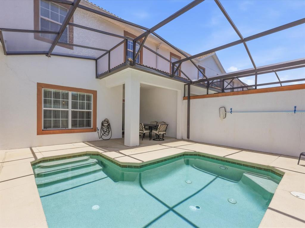 A swimming pool with steps sits on a patio enclosed by a screened-in lanai — 1562 MOON VALLEY DRIVE, DAVENPORT, FL