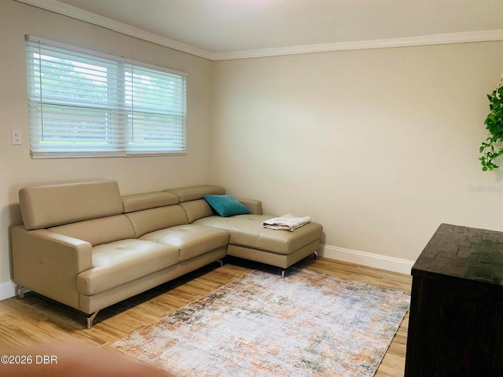 A living room features a beige sectional sofa, a patterned area rug, and wood-look flooring — 342 N CHARLES STREET, DAYTONA BEACH, FL