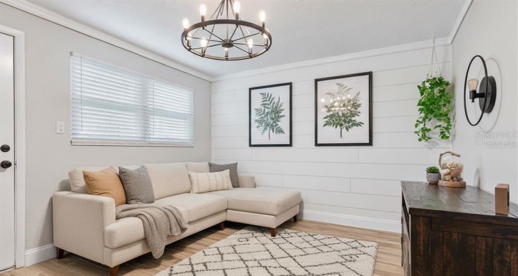 A living room features a sectional sofa, shiplap wall, chandelier, and a patterned area rug — 342 N CHARLES STREET, DAYTONA BEACH, FL
