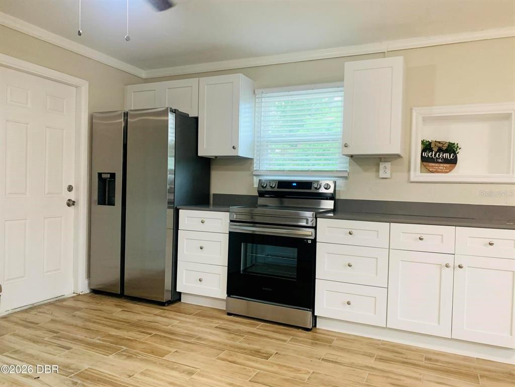 A kitchen features white cabinets, stainless steel appliances, gray countertops, and wood-look tile flooring — 342 N CHARLES STREET, DAYTONA BEACH, FL