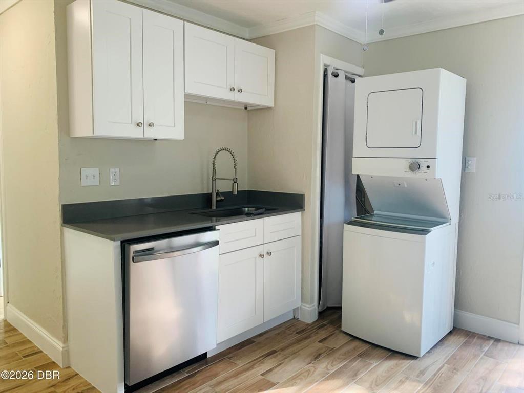 A laundry area features a stacked washer-dryer, a sink, and white cabinets with dark countertops — 342 N CHARLES STREET, DAYTONA BEACH, FL