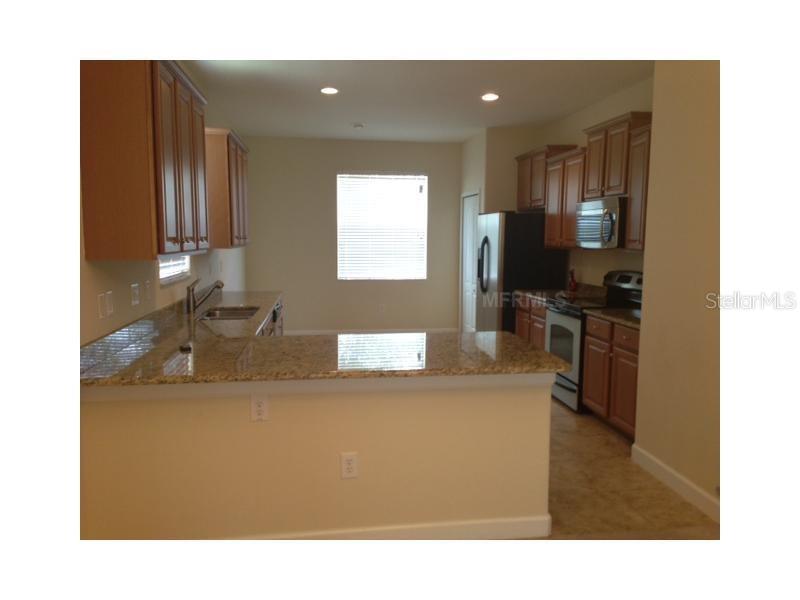 A kitchen features wooden cabinets, granite countertops, and stainless steel appliances — 14010 HOLLOW LEAF PLACE, RIVERVIEW, FL