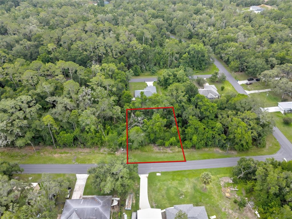 An aerial view shows a rectangular vacant lot outlined in red along a paved road — 1048 W MAXIMILIAN PLACE, CITRUS SPRINGS, FL