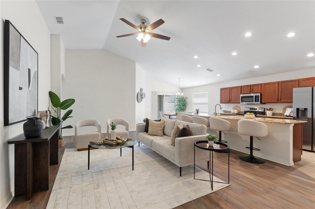 An open-concept living room and kitchen featuring wood-look flooring, a sofa, and a breakfast bar — 2009 DANES COURT, LAKELAND, FL