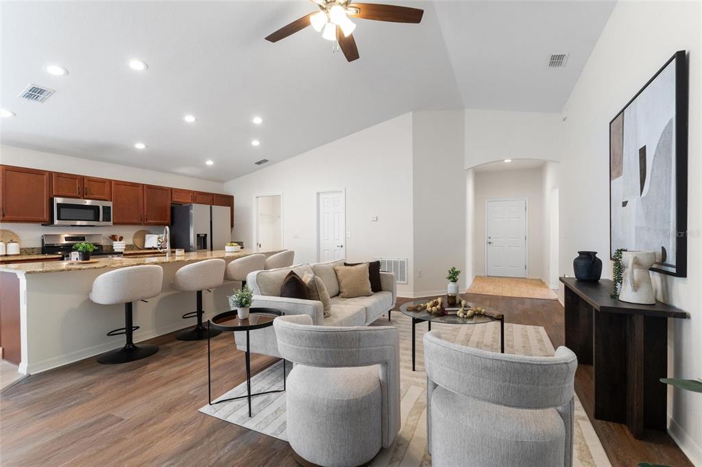 An open-concept living room and kitchen featuring wood-look flooring, light-colored furniture, and wooden cabinets — 2009 DANES COURT, LAKELAND, FL