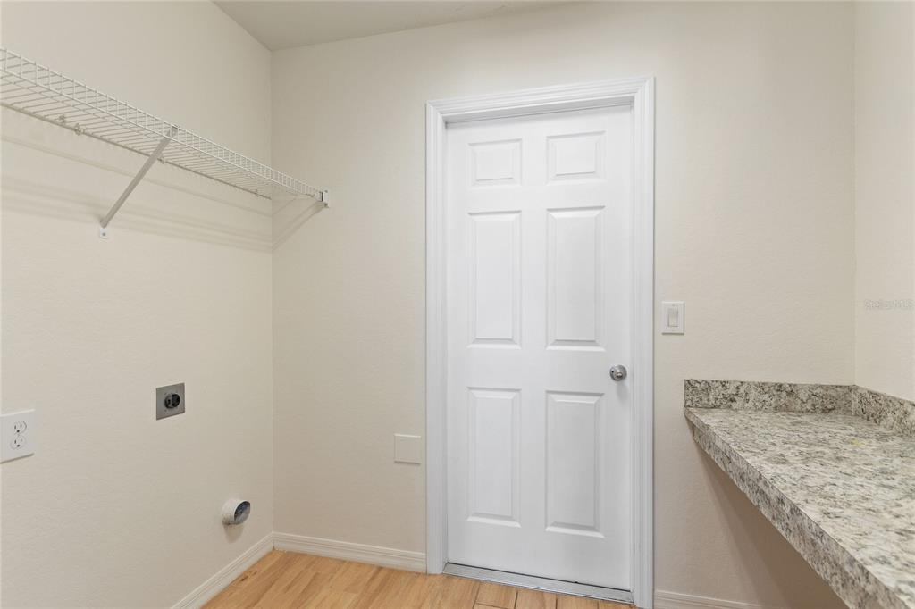 A laundry room with a white door, wire shelving, and a granite countertop — 2009 DANES COURT, LAKELAND, FL