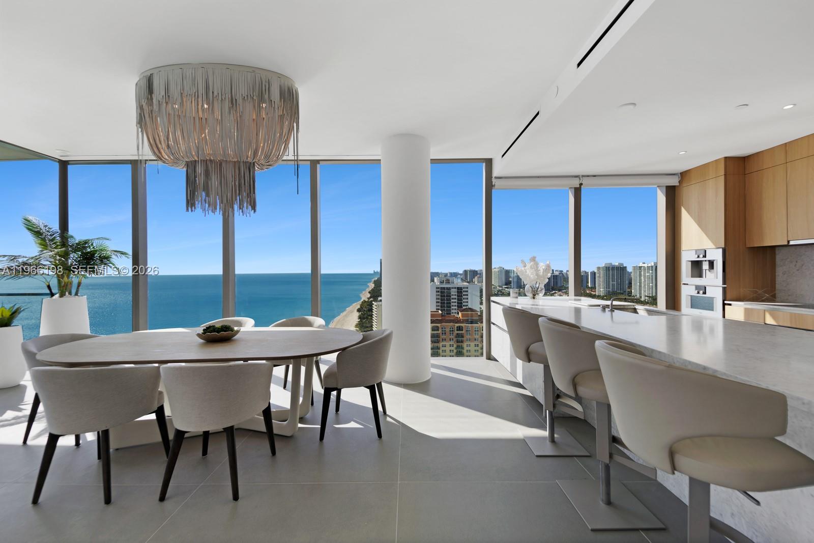 A modern dining area and kitchen feature floor-to-ceiling windows with ocean and city views — 2000 S Ocean Dr # 25B, Hallandale Beach FL 33009, HALLANDALE BEACH, FL
