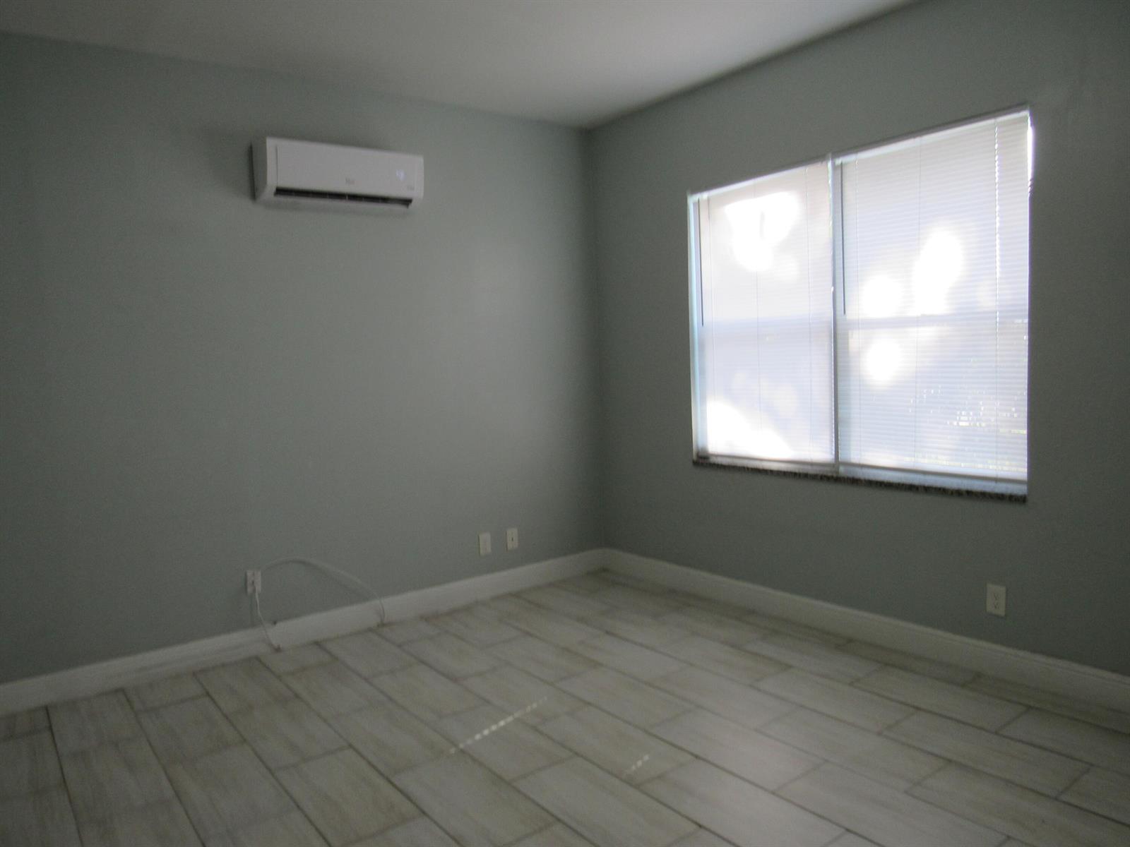 An empty room with light gray walls, tile flooring, a window with blinds, and an AC unit — 4283 Cocoanut Road # 3, West Palm Beach FL 33406, WEST PALM BEACH, FL