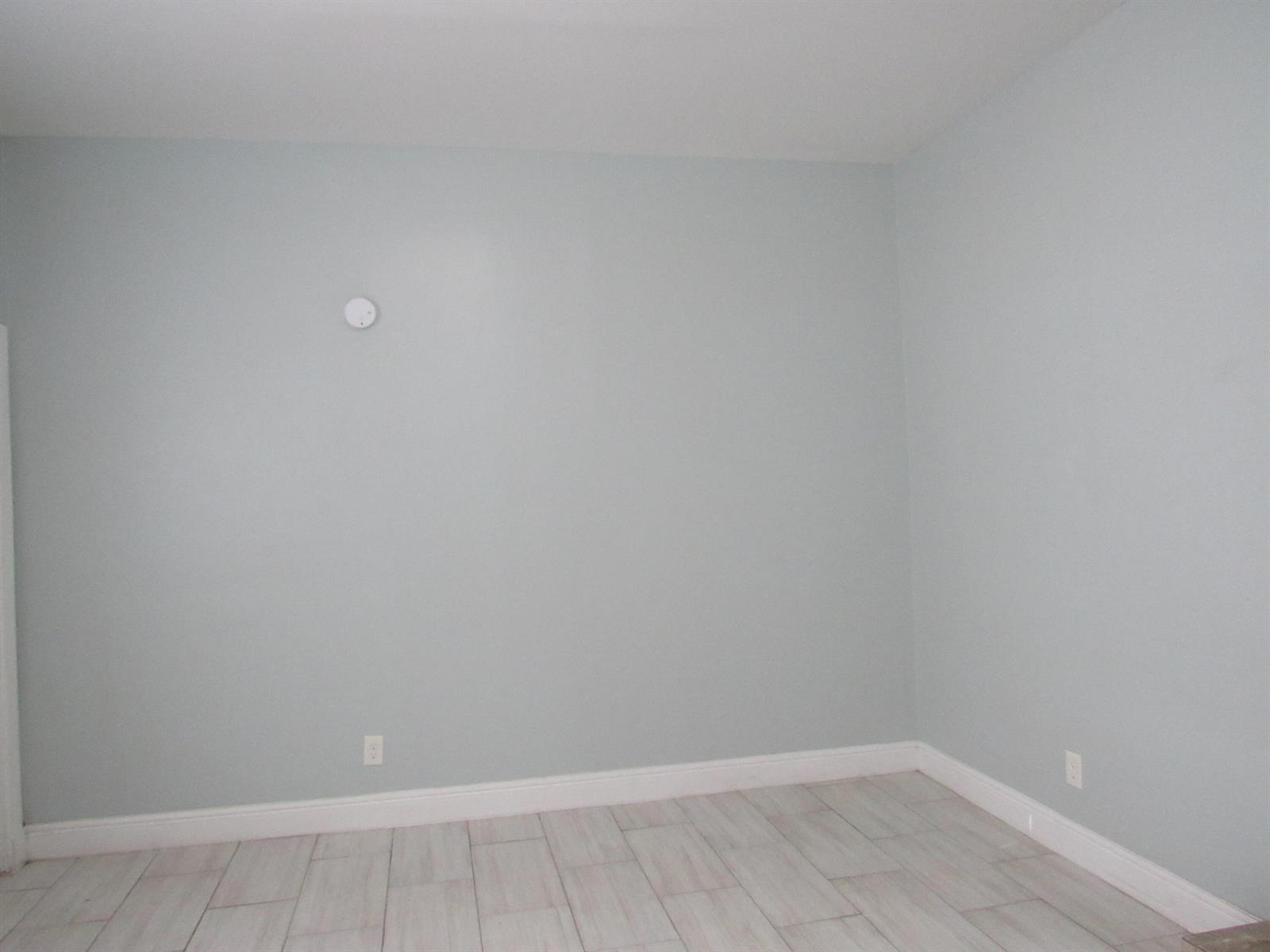 An empty room features light blue walls, white baseboards, and light-colored wood-look tile flooring — 4283 Cocoanut Road # 3, West Palm Beach FL 33406, WEST PALM BEACH, FL