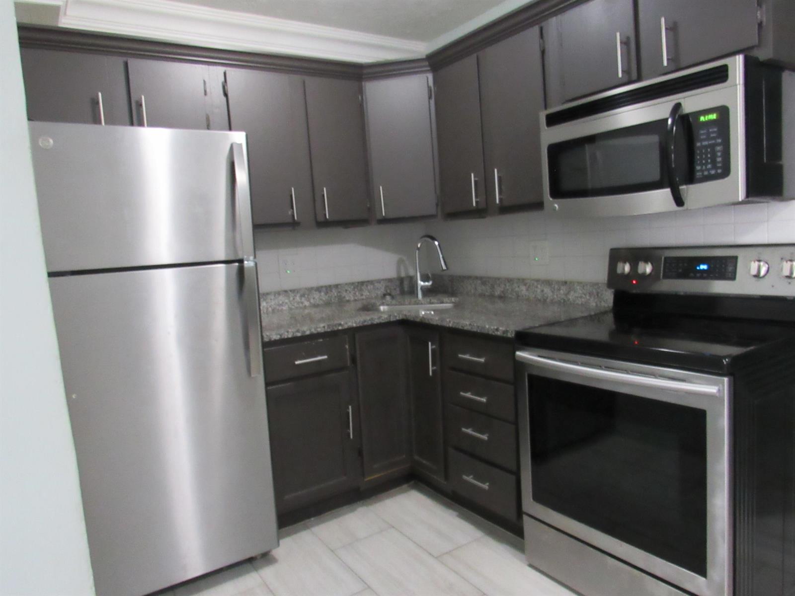 A kitchen features dark cabinets, stainless steel appliances, and granite countertops — 4283 Cocoanut Road # 3, West Palm Beach FL 33406, WEST PALM BEACH, FL