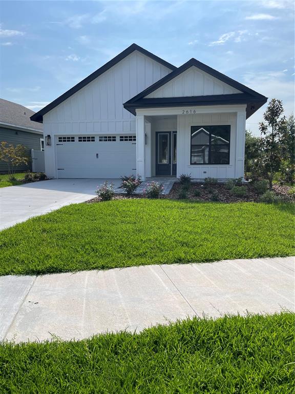 A single-story white house with a gabled roof, a garage, and a front porch — 122 SW 212TH DRIVE, NEWBERRY, FL