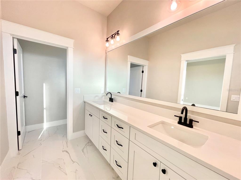 A modern bathroom features a double vanity with white cabinets, black fixtures, and a large mirror — 122 SW 212TH DRIVE, NEWBERRY, FL