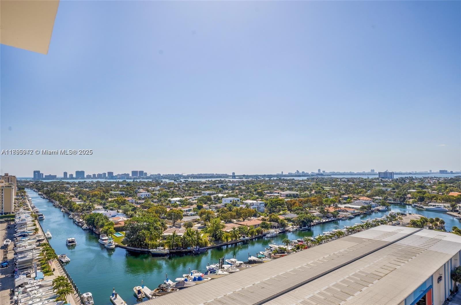 An elevated view shows a canal lined with boats and residential homes under a clear sky — 13499 Biscayne Blvd # 1603, North Miami FL 33181, NORTH MIAMI, FL