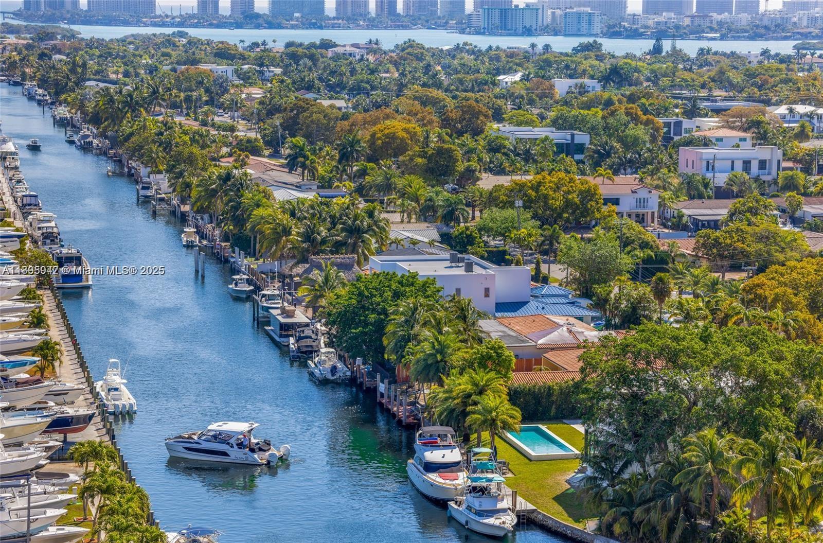 An aerial view shows a canal lined with private docks, boats, and waterfront homes — 13499 Biscayne Blvd # 1603, North Miami FL 33181, NORTH MIAMI, FL