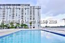A rectangular swimming pool sits in the foreground with a tall apartment building behind it — 13499 Biscayne Blvd # 1603, North Miami FL 33181, NORTH MIAMI, FL