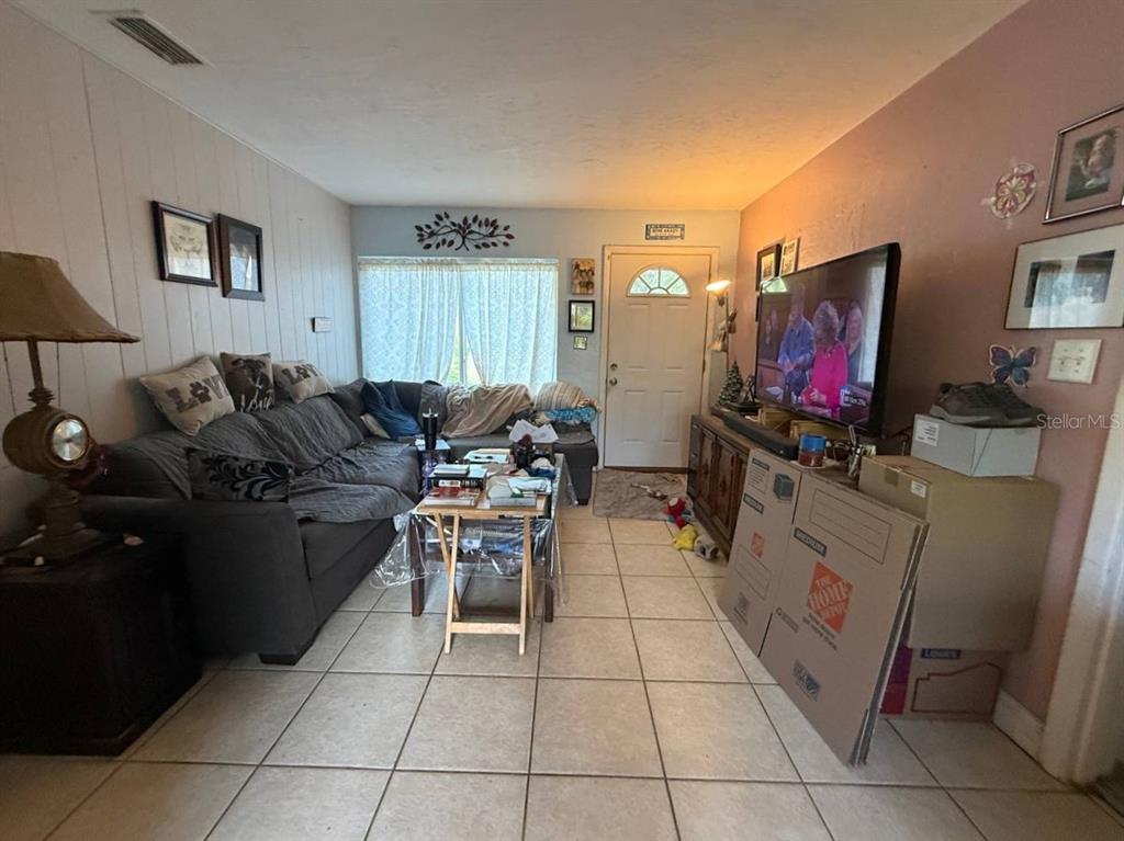 A living room with tile flooring, a gray sectional sofa, and a television on a console — 1032 NE 20TH AVENUE, GAINESVILLE, FL