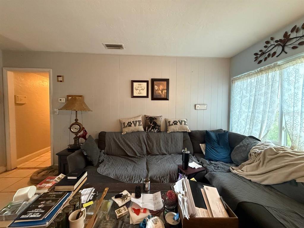 A living room features a large gray sectional sofa, a coffee table with clutter, and wall decor — 1032 NE 20TH AVENUE, GAINESVILLE, FL