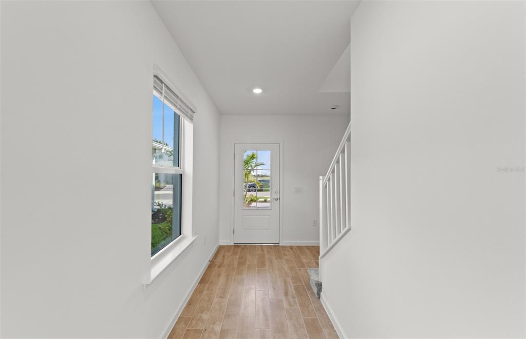 A bright entryway features light wood-look tile flooring, white walls, a window, and a staircase — 759 BALLEBY TRAIL, BRADENTON, FL